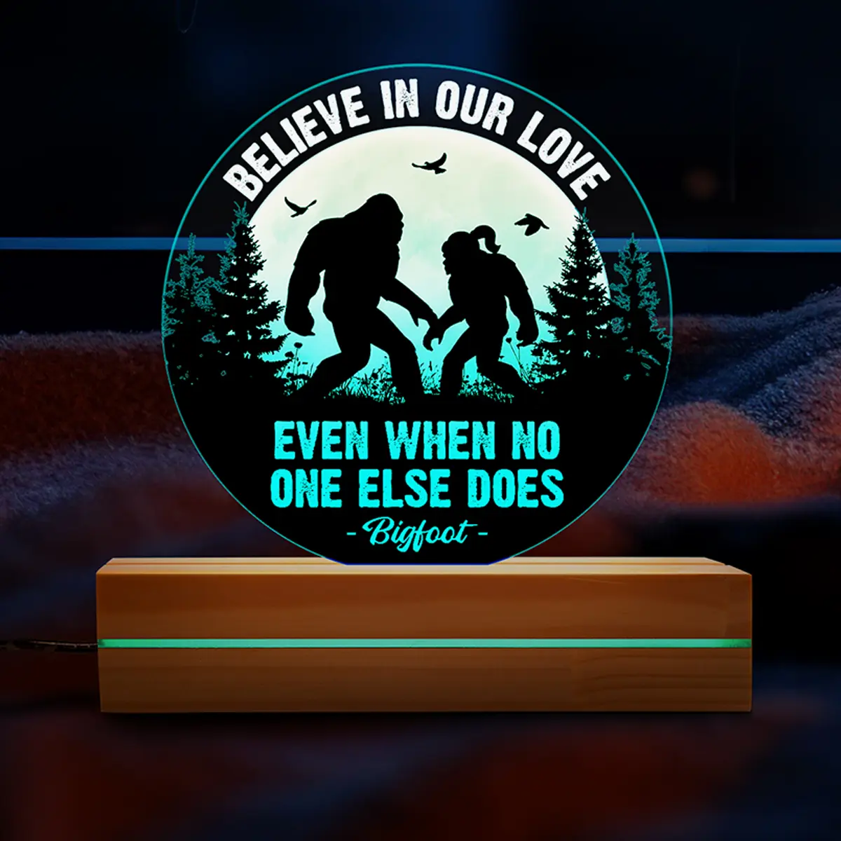 Personalized Bigfoot-themed night light featuring two Bigfoot silhouettes holding hands under a full moon, with the quote 'Believe in Our Love Even When No One Else Does,' customizable on a wooden base